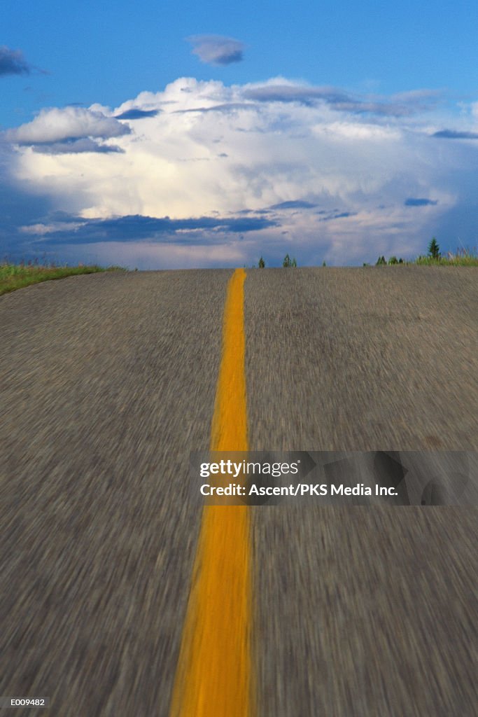 Road at top of hill with clouds in background