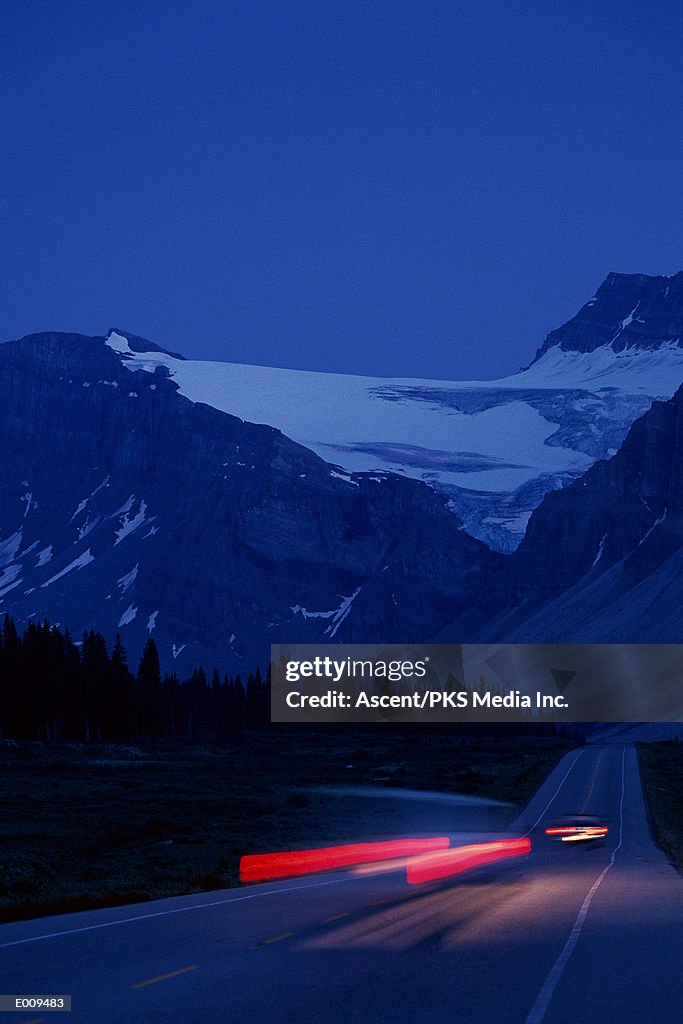 Mountain highway in evening with streaked taillights