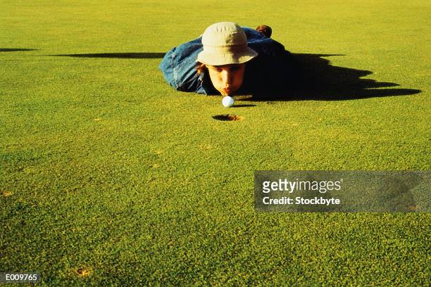 young man blowing golf ball into hole - golf cheating stock pictures, royalty-free photos & images