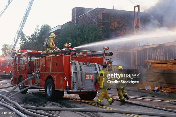 firefighters dousing building - brandweerwagen stockfoto's en -beelden