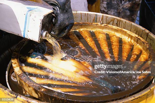 hazardous waste being poured into steel container - drum container stock-fotos und bilder