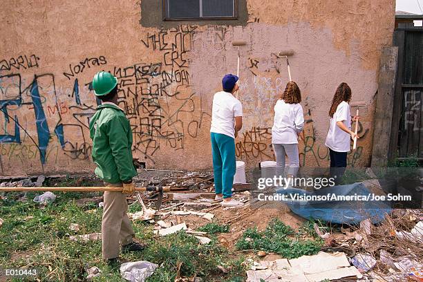 people painting over graffiti on apartment building - city cleaning 個照片及圖片檔