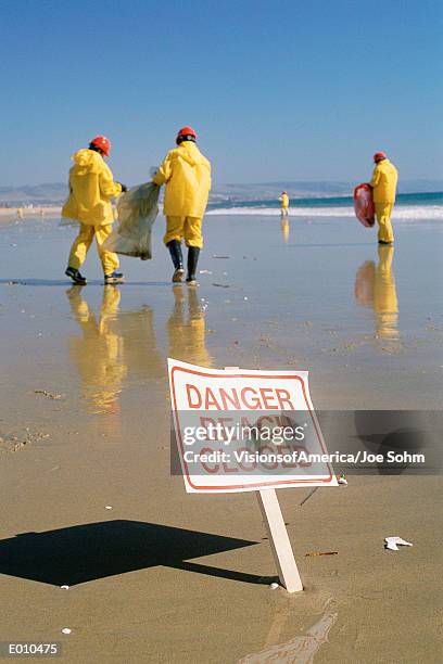 clean-up crew on beach and warning signage - activists holds candlelight vigil to mark 1 month anniversary of oil spill stockfoto's en -beelden