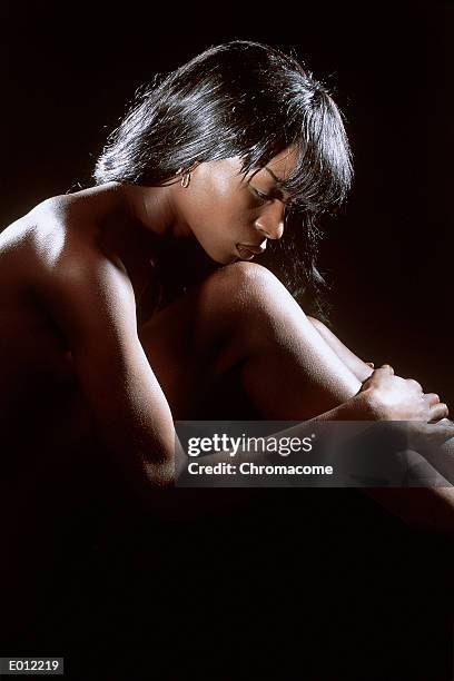 profile of african american woman hugging knees - gestalt stock-fotos und bilder