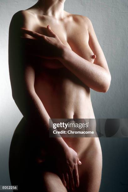 standing nude female, hands covering one breast and pelvis - curvy woman photos et images de collection