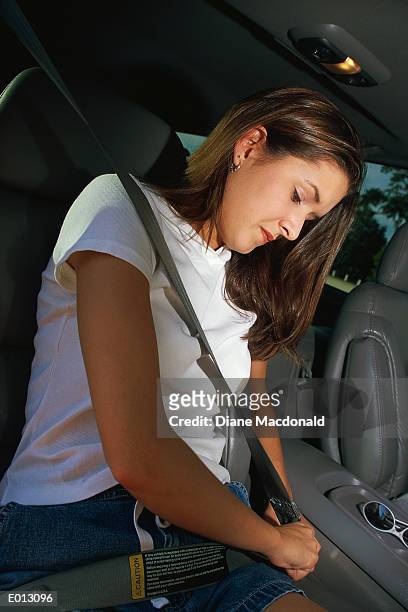 young woman adjusting seatbelt in passenger seat - diane ストックフォトと画像