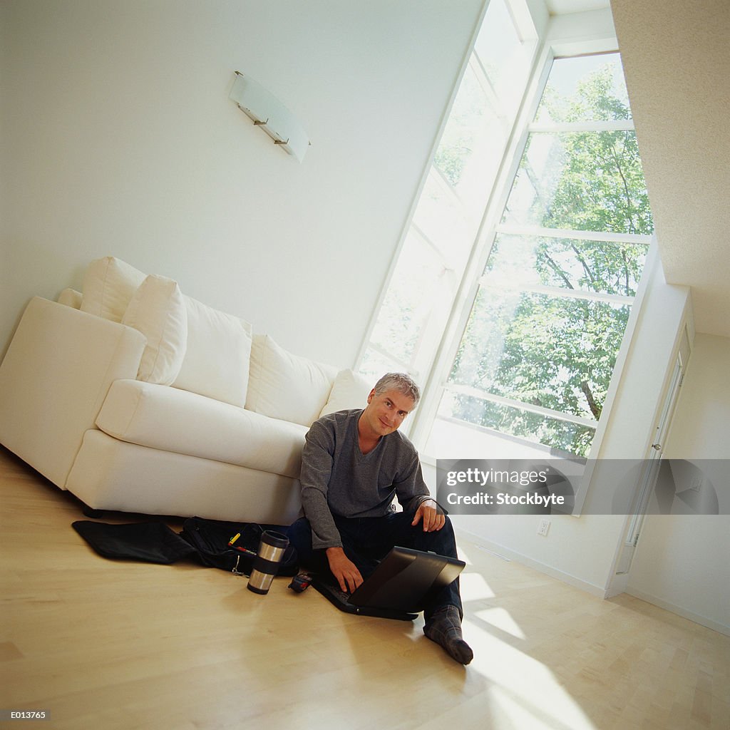 Angled View of Man Sitting on Floor with Laptop