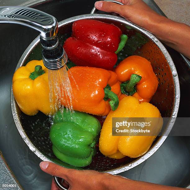 washing bell peppers - orangefarbige paprika stock-fotos und bilder