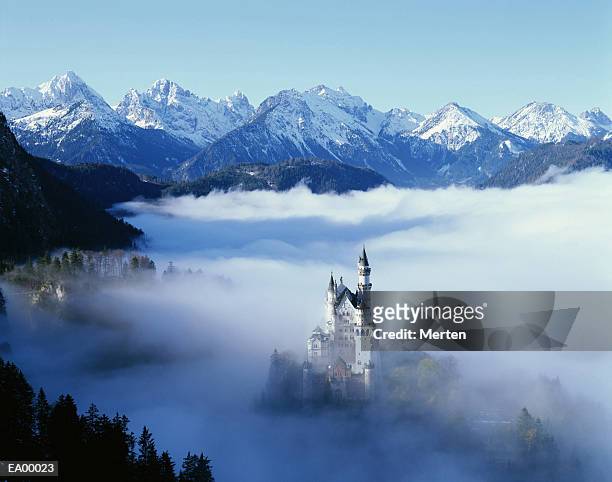 neuschwanstein castle in mist, with mountains behind / bavaria bavaria - neuschwanstein stock-fotos und bilder