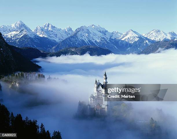 neuschwanstein castle in mist, with mountains behind / bavaria bavaria - bavaria stockfoto's en -beelden