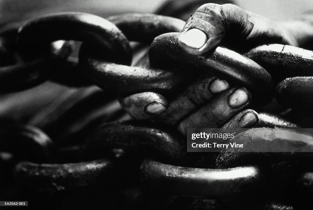 Worker's hands holding chains, close-up (B&W)