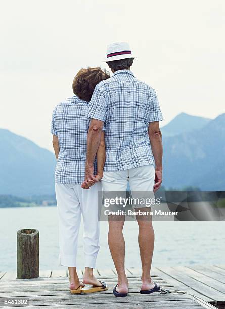 mature couple on jetty looking out across lake, rear view - maurer stock pictures, royalty-free photos & images