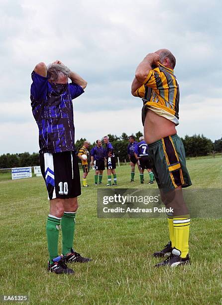 two mature male footballers exchanging shirts on pitch - amateur stock-fotos und bilder