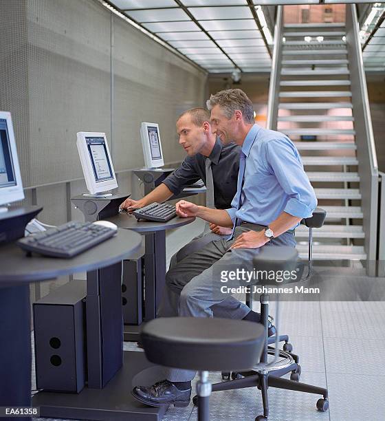 two businessmen looking at computer screen - mann stock pictures, royalty-free photos & images