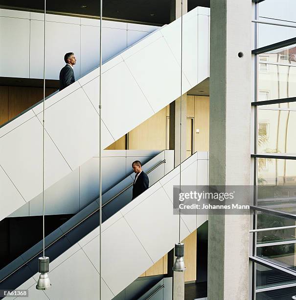 businessmen walking up and down staircase - mann stockfoto's en -beelden