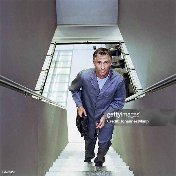 man climbing stairs holding extension cable, elevated view - mann stock pictures, royalty-free photos & images