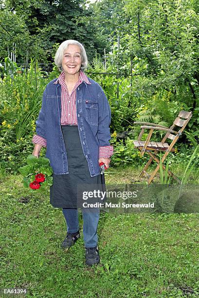 elderly woman in garden, holding secateurs and plant, portrait - spreewald stock-fotos und bilder