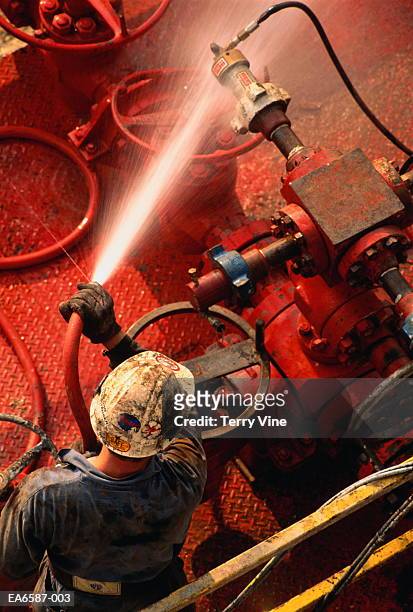 worker hosing down equipment on oil rig, overhead view - oil rig worker stock pictures, royalty-free photos & images