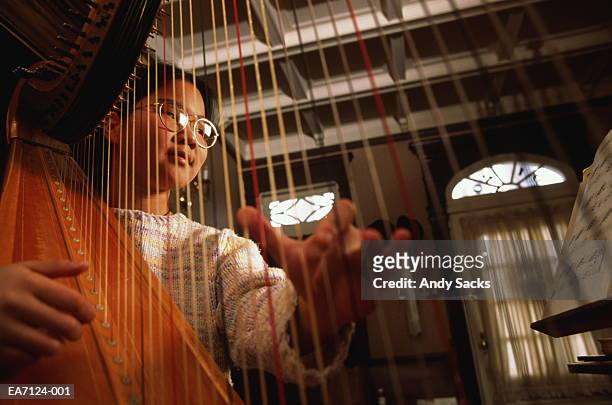 teenage girl (12-14) playing harp at home - classical musician stock pictures, royalty-free photos & images