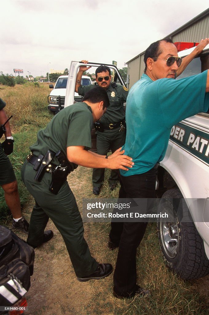 U.S. Border Patrol agent frisking caught illegal alien, Texas, USA
