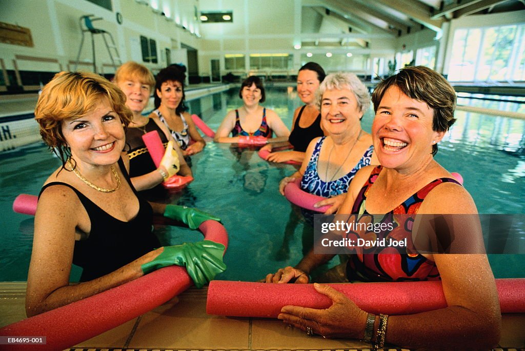 Mature women with plastic tubes in water exercise class