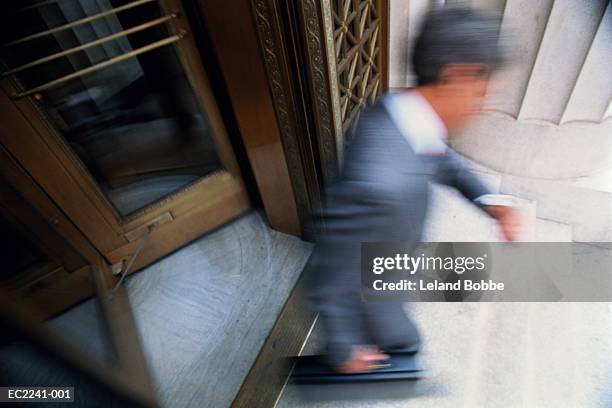 businessman walking out of revolving door (blurred motion) - revolving door stock pictures, royalty-free photos & images