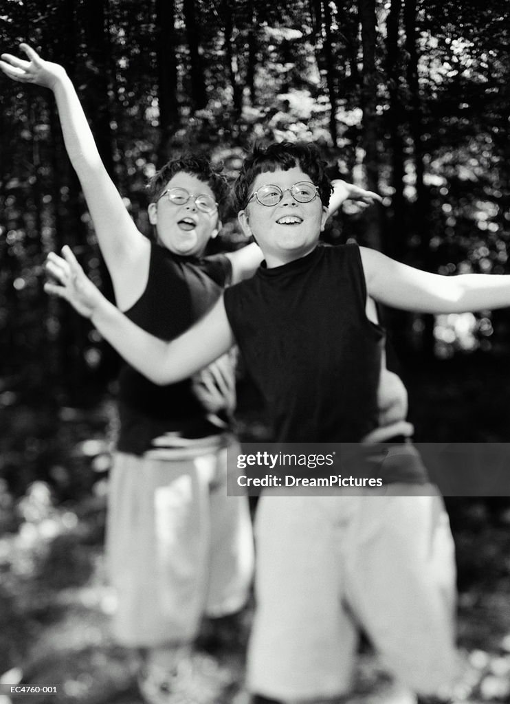 Young identical twin boys (7-9) wearing glasses outdoors (B&W)
