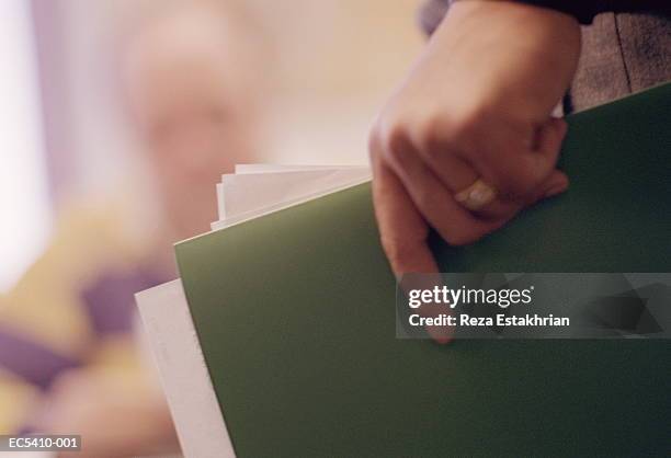 hand holding green folder and papers, close-up (enhancement) - map stockfoto's en -beelden