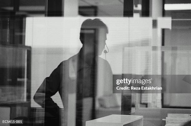 silhouette of businessman wearing headphones in office (enhancement) - black and white office stock pictures, royalty-free photos & images