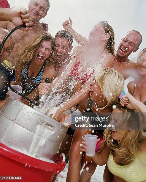 group of young adults being sprayed by beer keg - spring break stock pictures, royalty-free photos & images