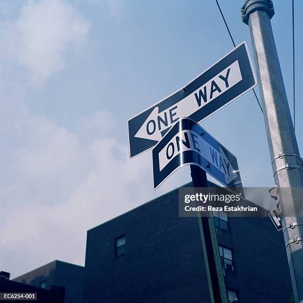 'one way' signs, one bent, low angle view - einbahnstraßenschild stock-fotos und bilder
