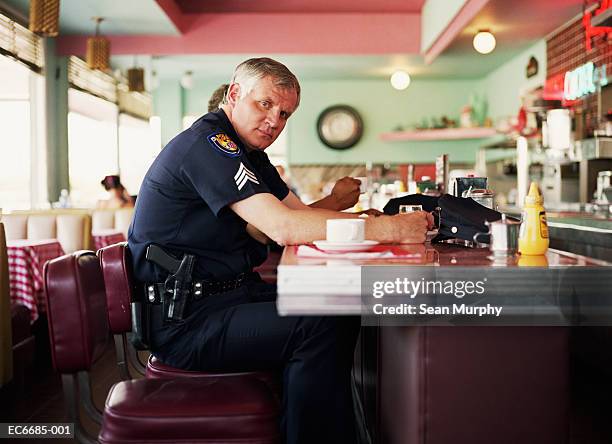 policeman sitting having coffee at bar in diner - diner stock pictures, royalty-free photos & images