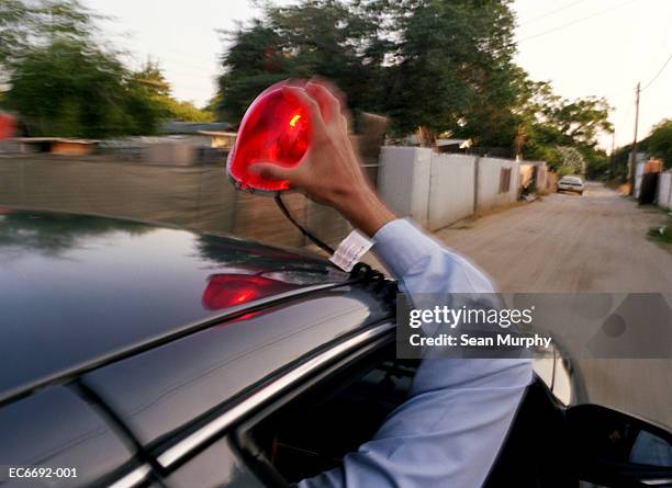 policemen in car chase, one putting light on roof of car - cop car photos et images de collection