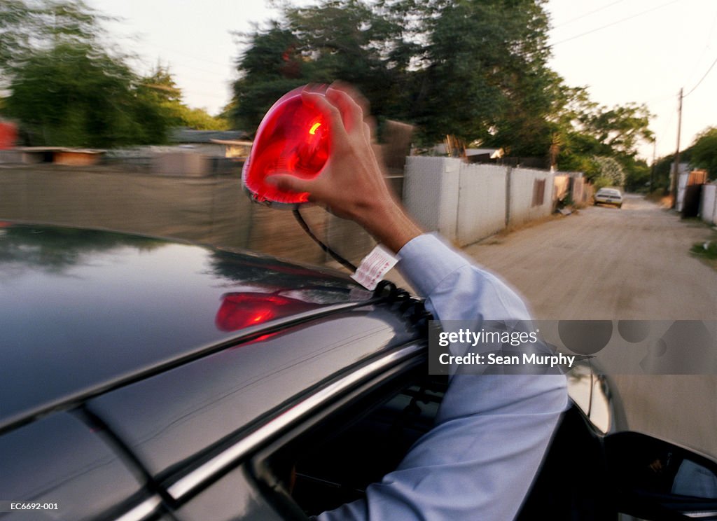 Policemen in car chase, one putting light on roof of car