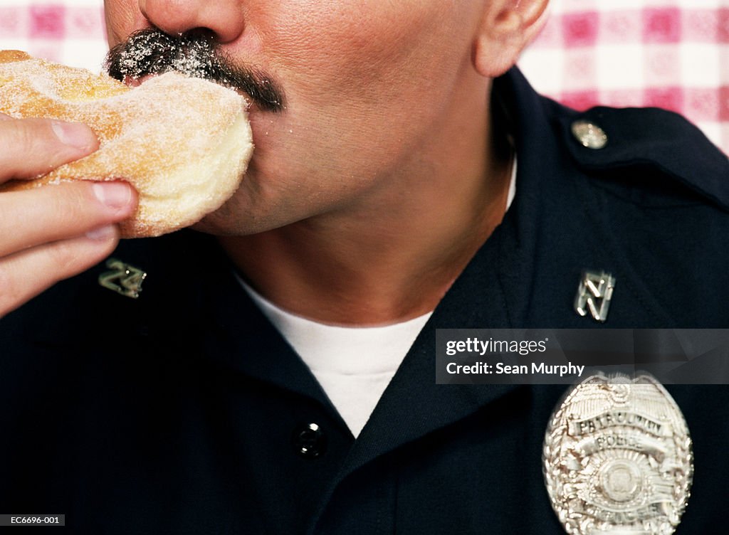 Policeman eating sugared doughnut, close-up