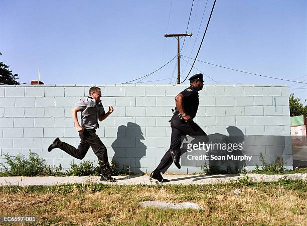 man chasing police officer down sidewalk - chasing stock-fotos und bilder