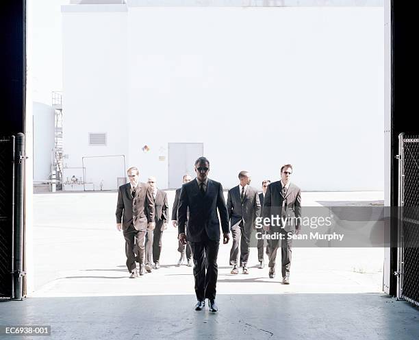 men in black suits entering industrial building - mafia stockfoto's en -beelden