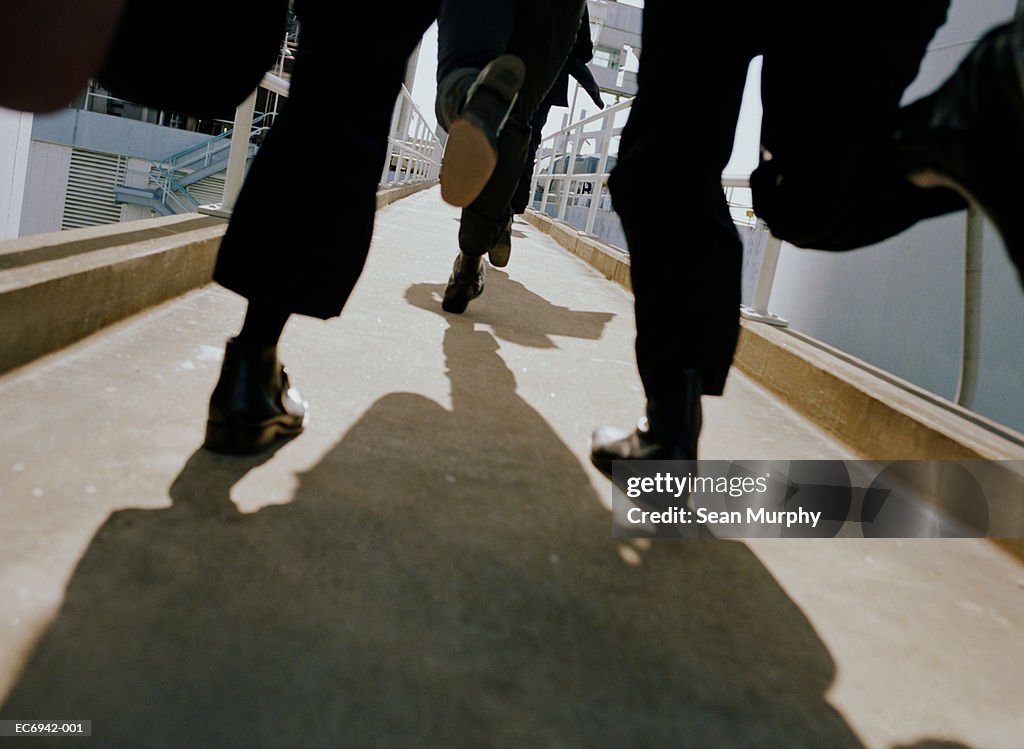 Men in black suits running on walkway, low angle view
