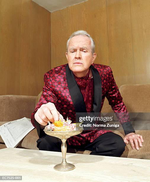 mature man wearing silk robe, picking candy from dish - smoking jacket 個照片及圖片檔