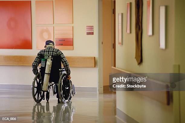 elderly man in hospital corridor in wheelchair, oxygen tank on back - tanque de oxigénio imagens e fotografias de stock