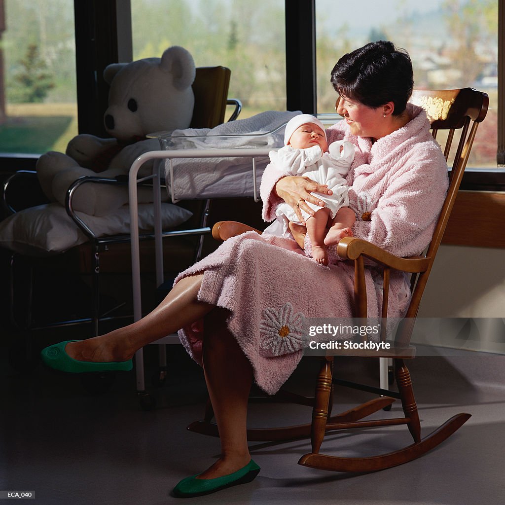 Mother holding newborn baby, sitting in rocking chair