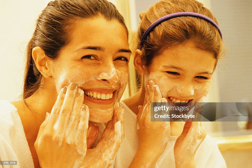 Mother and daughter washing faces and smiling