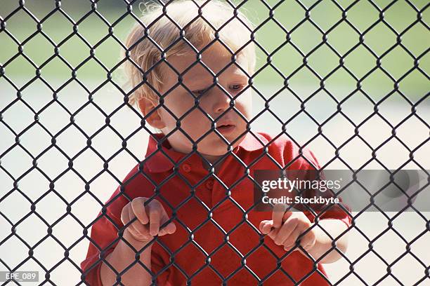 boy looking through chainlink fence - criss cross fence stock pictures, royalty-free photos & images