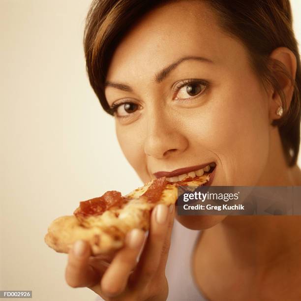 woman eating a slice of pizza - greg stock pictures, royalty-free photos & images