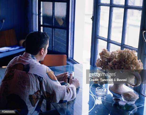 man drinking by window - bavosi ストックフォトと画像