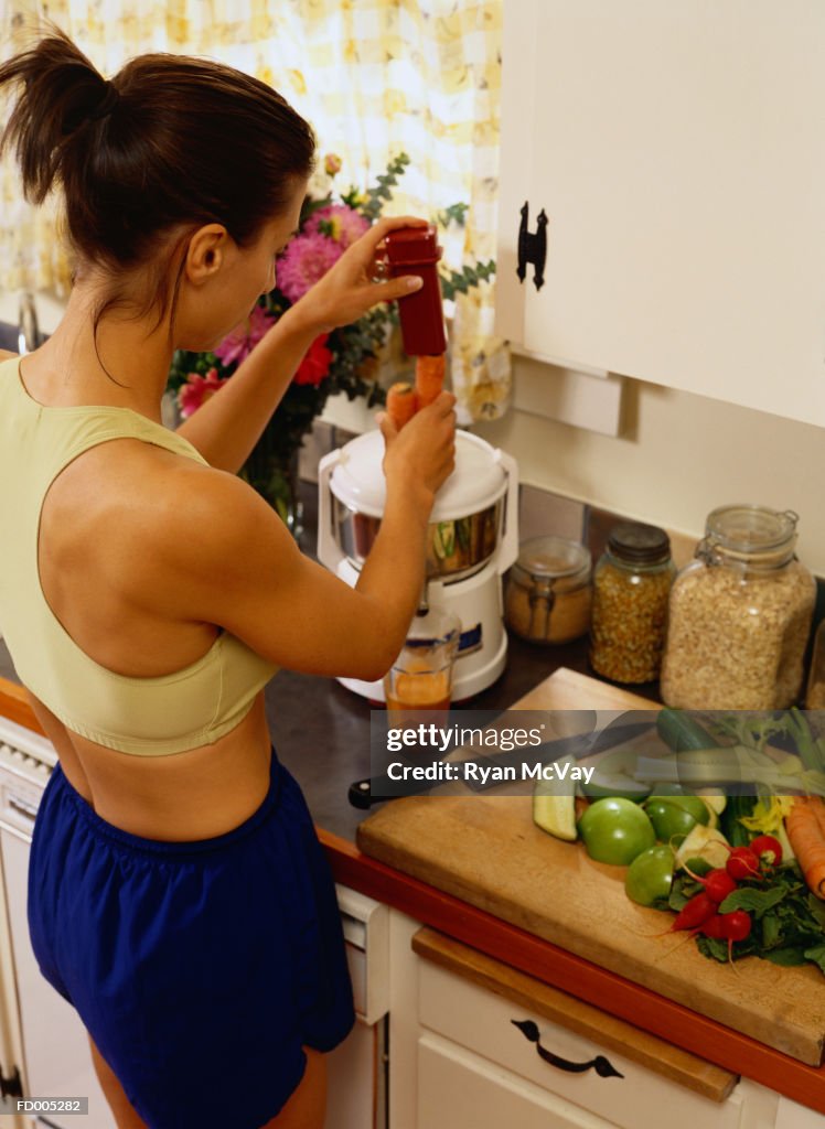 Woman Putting Carrots in a Juicer