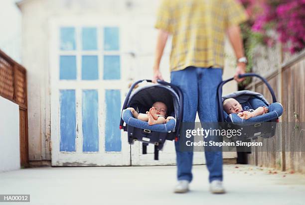 father holding baby twins (10-12 months) in car seats, low section - stehen stock pictures, royalty-free photos & images