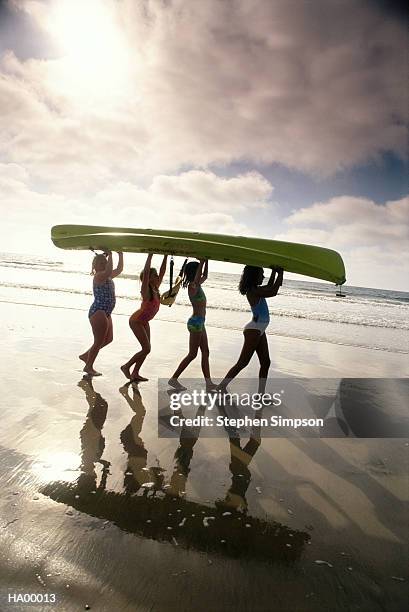 four girls (9-11) carrying kayak into water - stehen stock pictures, royalty-free photos & images