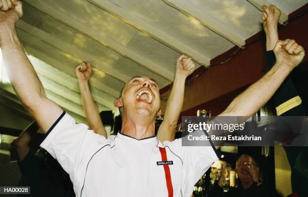 cheering football fan watching match in pub, arms raised, close-up - supporter fotografías e imágenes de stock