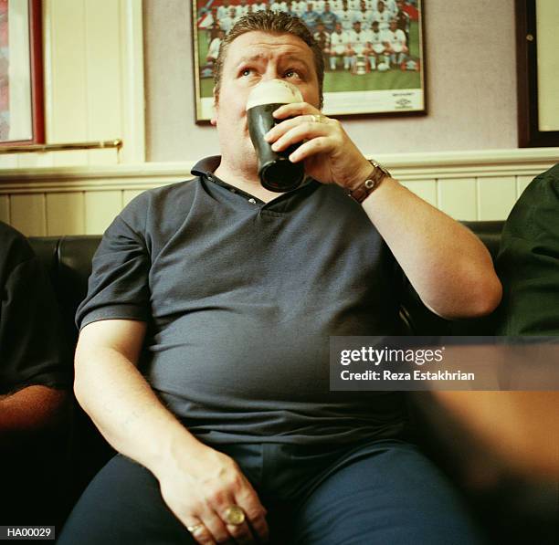 man drinking pint in pub, close-up - bierbauch stock-fotos und bilder